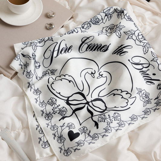 27x27 ivory silk wedding scarf with black floral, heart and swan motifs reading “Here Comes the Bride”
