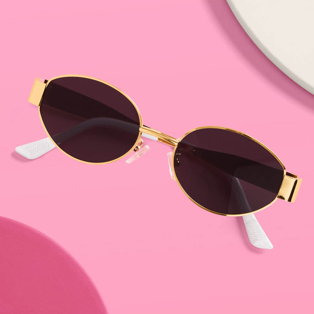 Gold-framed sunglasses with dark lenses on a pink background