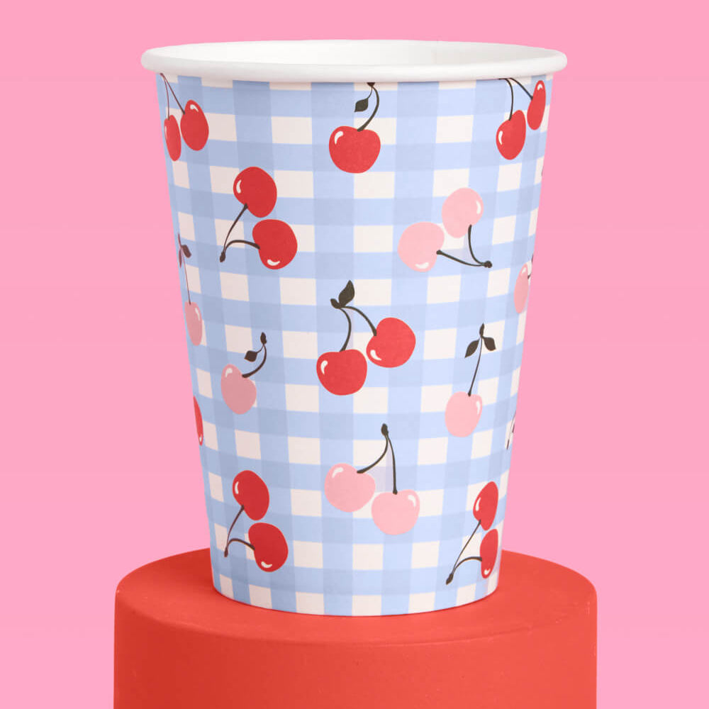 Paper cup with cherry pattern on a pink background