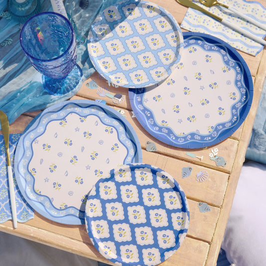 Blue floral paper plates styled on wooden table with blue glassware and coastal decor