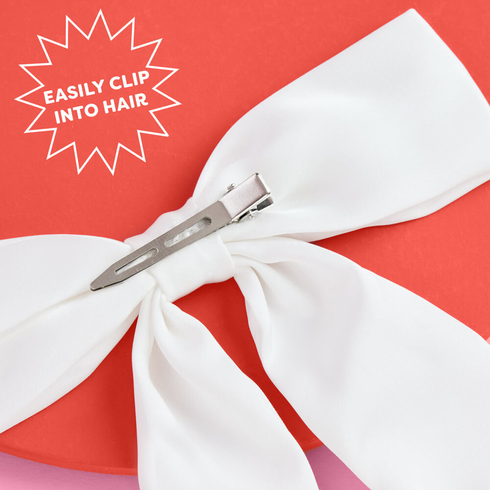 White hair bow with a clip on a red and pink background