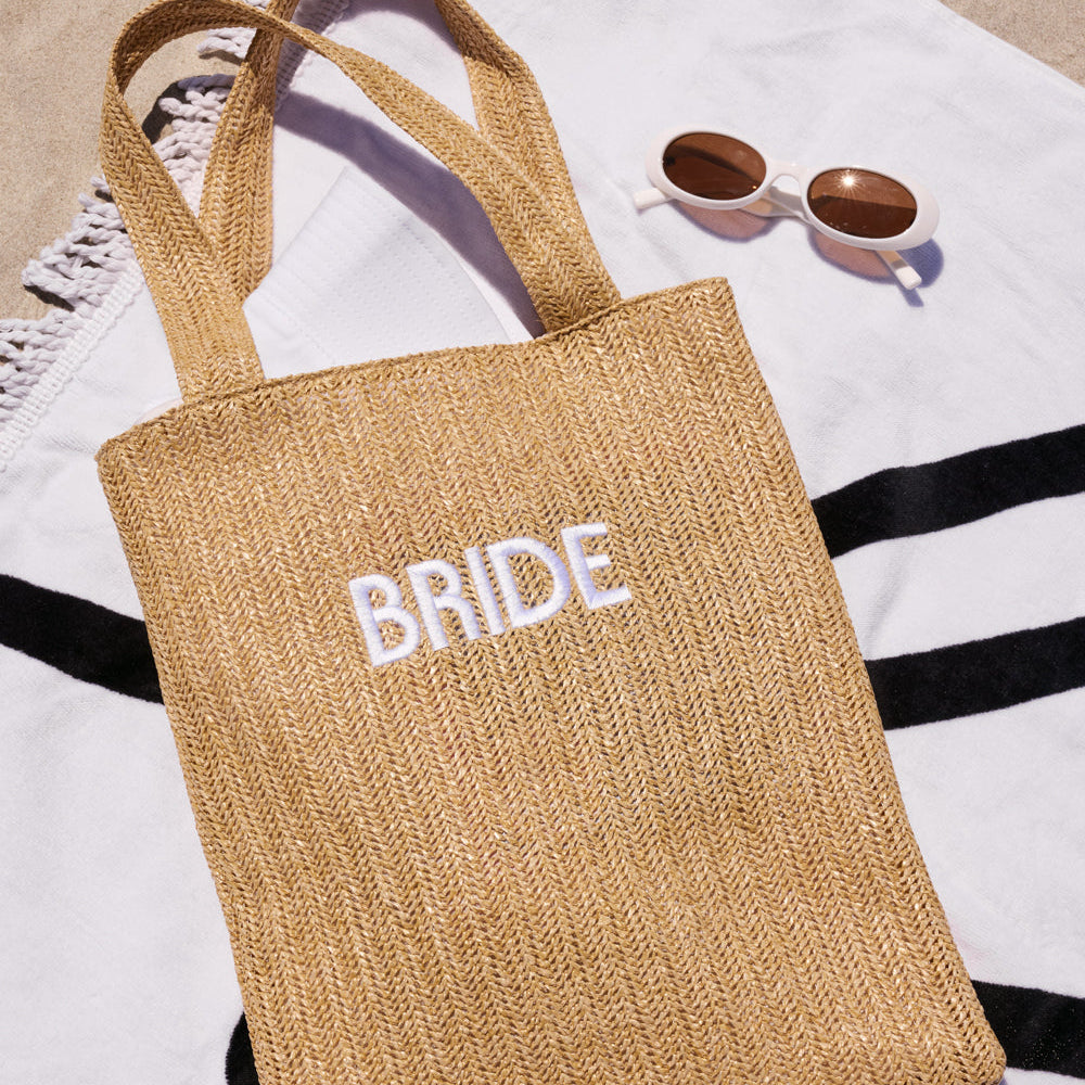 Beige tote bag with 'BRIDE' embroidery on a striped fabric background