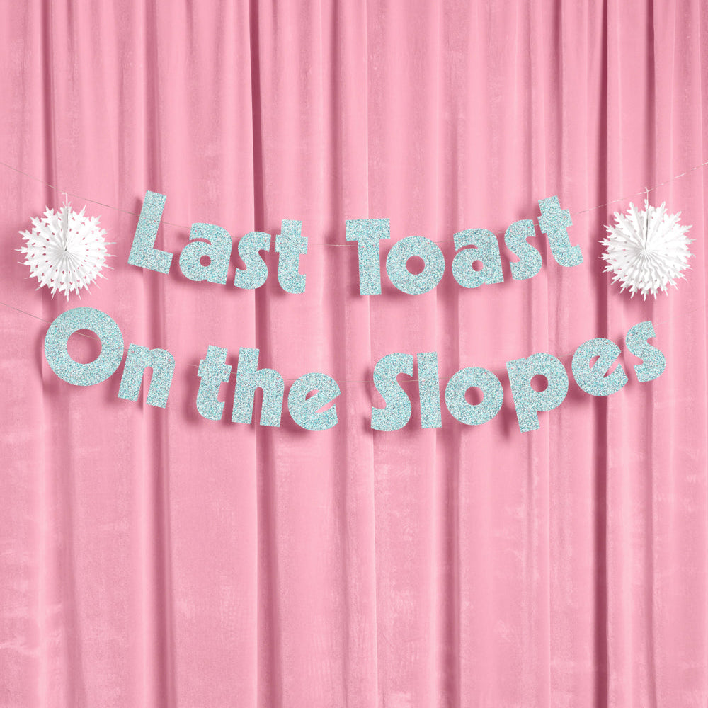 Text 'Last Toast On the Slopes' on a pink curtain background with decorative elements.