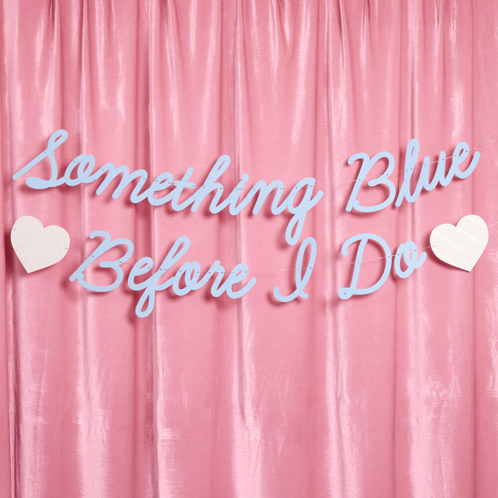 Decorative text 'Something Blue Before I Do' with hearts on a pink curtain background