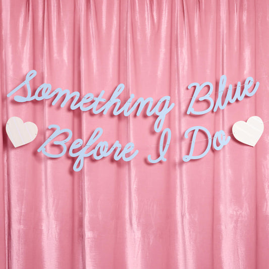 Decorative text 'Something Blue Before I Do' with hearts on a pink curtain background