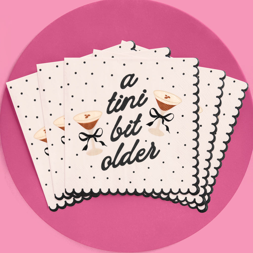 Stack of napkins with 'a tini bit older' text on a pink background