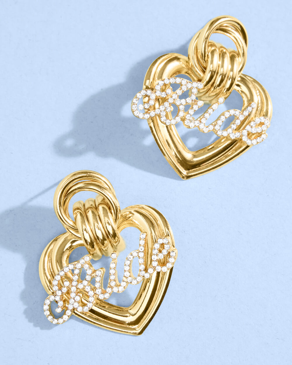 Gold heart-shaped earrings with interlocking design on a light blue background