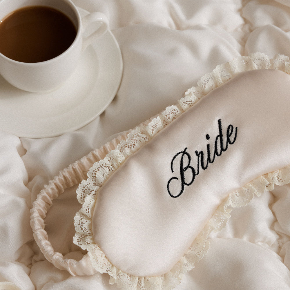Lace headband with 'Bride' embroidery on a textured surface next to a cup of coffee.