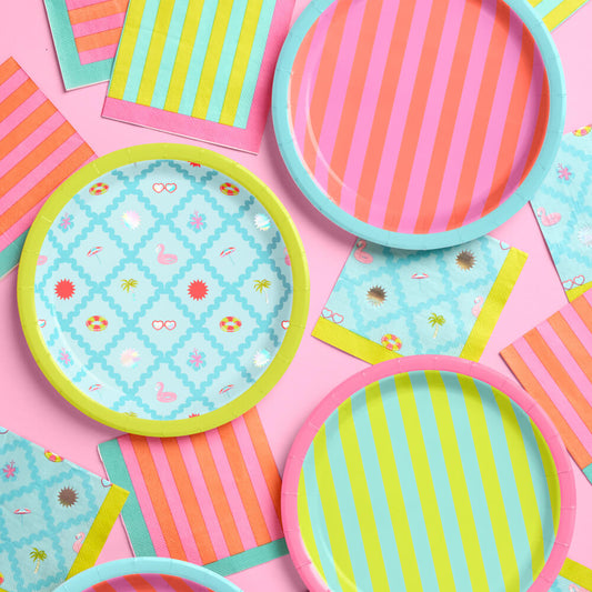 Colorful paper plates and napkins with patterns on a pink background