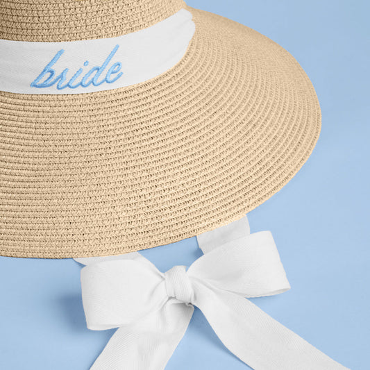 Straw hat with 'bride' embroidery and white ribbon on a blue background