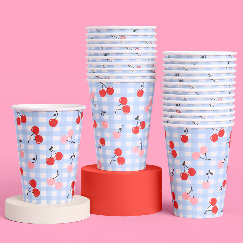 Stacks of paper cups with cherry pattern on a pink background