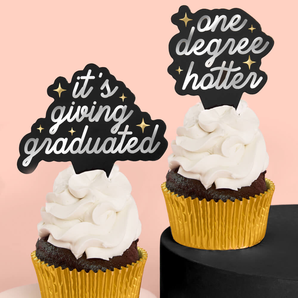 Two cupcakes with decorative toppers on a pink background