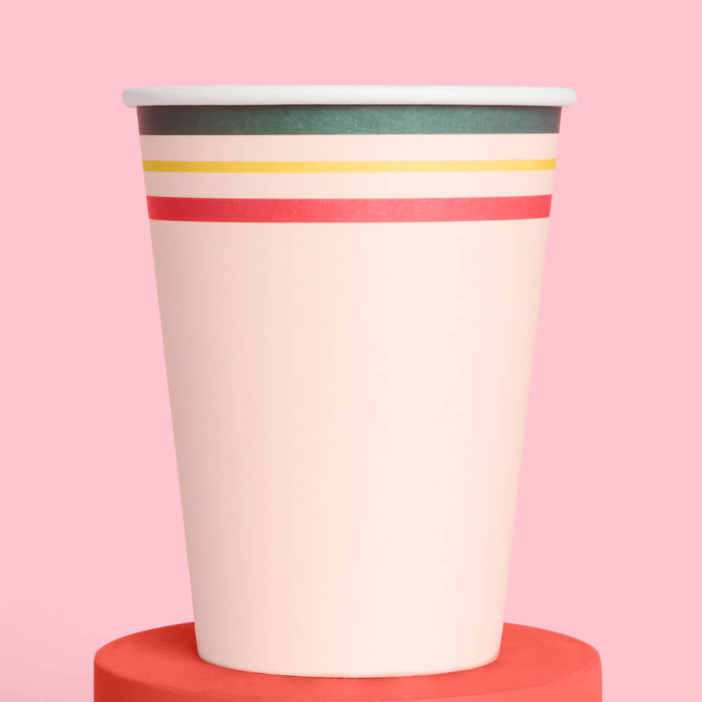 Paper cup with colorful stripes on a pink background