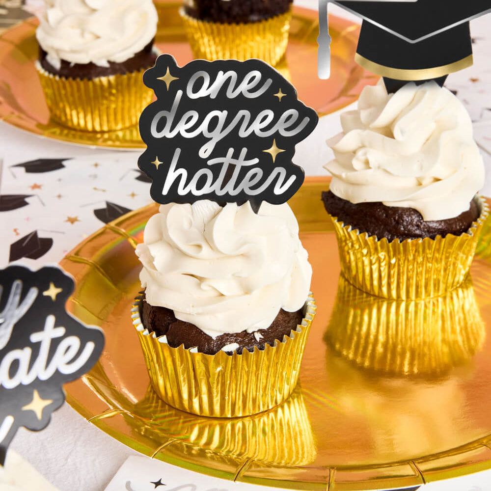 Cupcakes with gold wrappers and white frosting on a decorative plate with 'one degree hotter' topper.