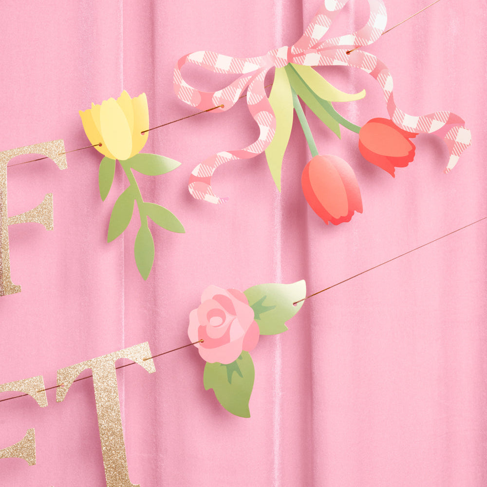 Decorative string with flowers and ribbons on a pink background