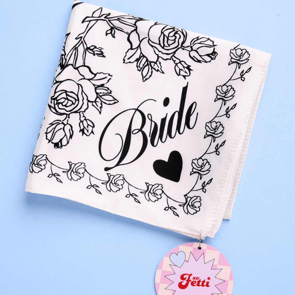 Ivory silk bridal scarf with black swan and “Bride” script design folded on blue background