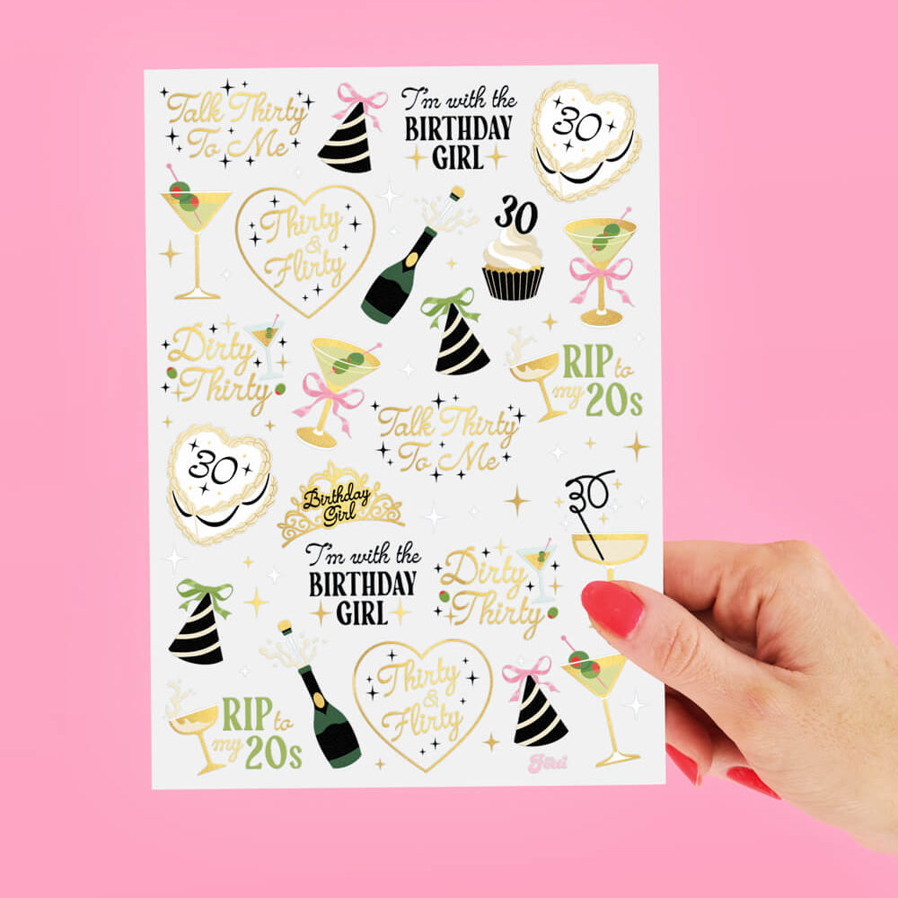 Sheet of birthday-themed temporary tattoos held against a pink background