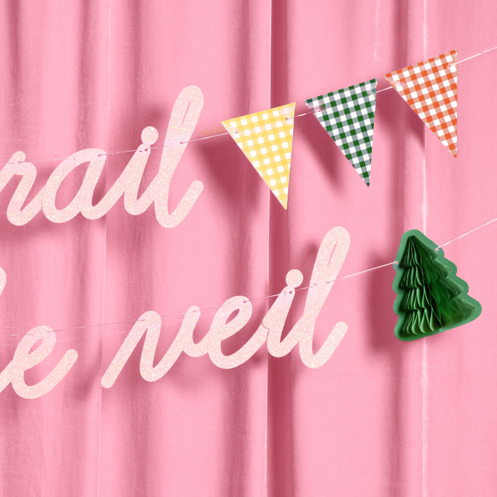 Colorful triangle flags and a green Christmas tree ornament on a pink curtain with text.