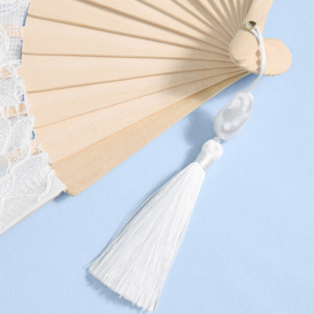 Beige hand fan with a white tassel on a light blue background