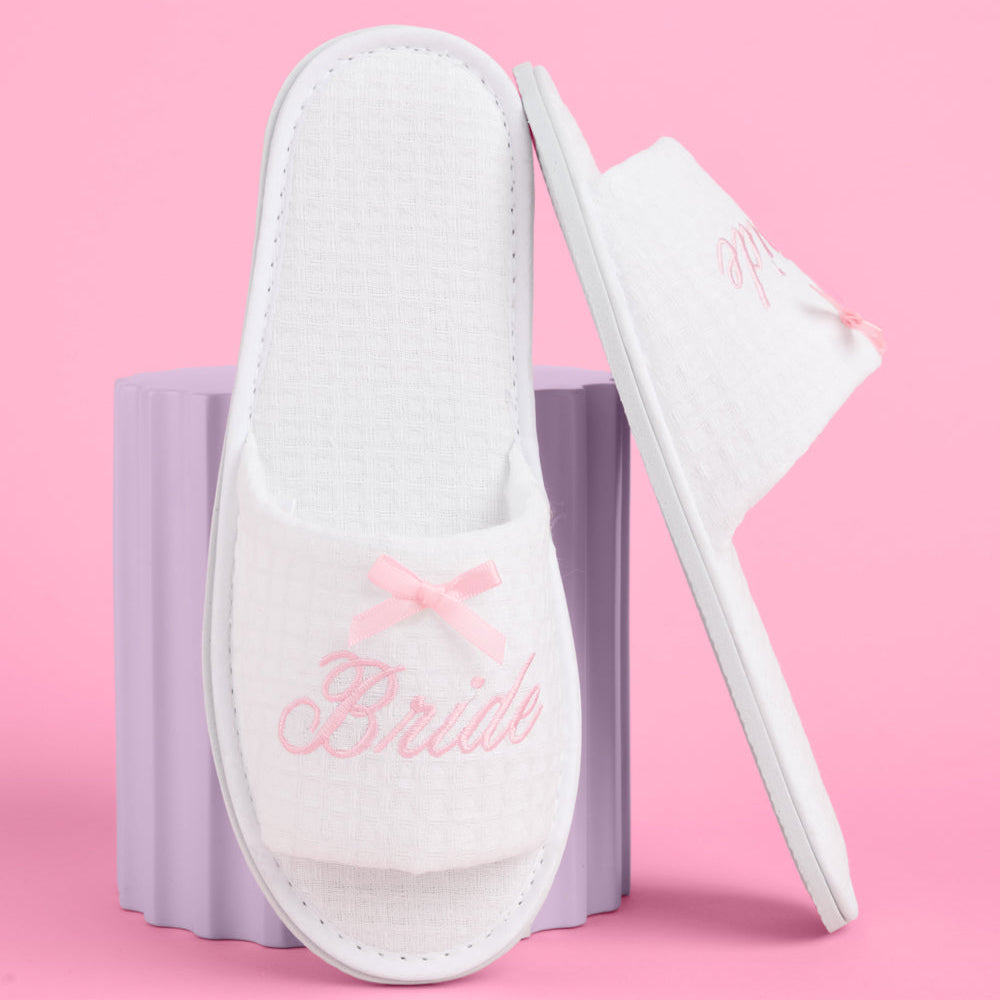 White slippers with 'Bride' embroidery on a pink background