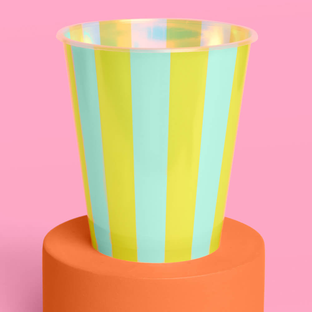 Colorful striped cup on an orange stand with a pink background