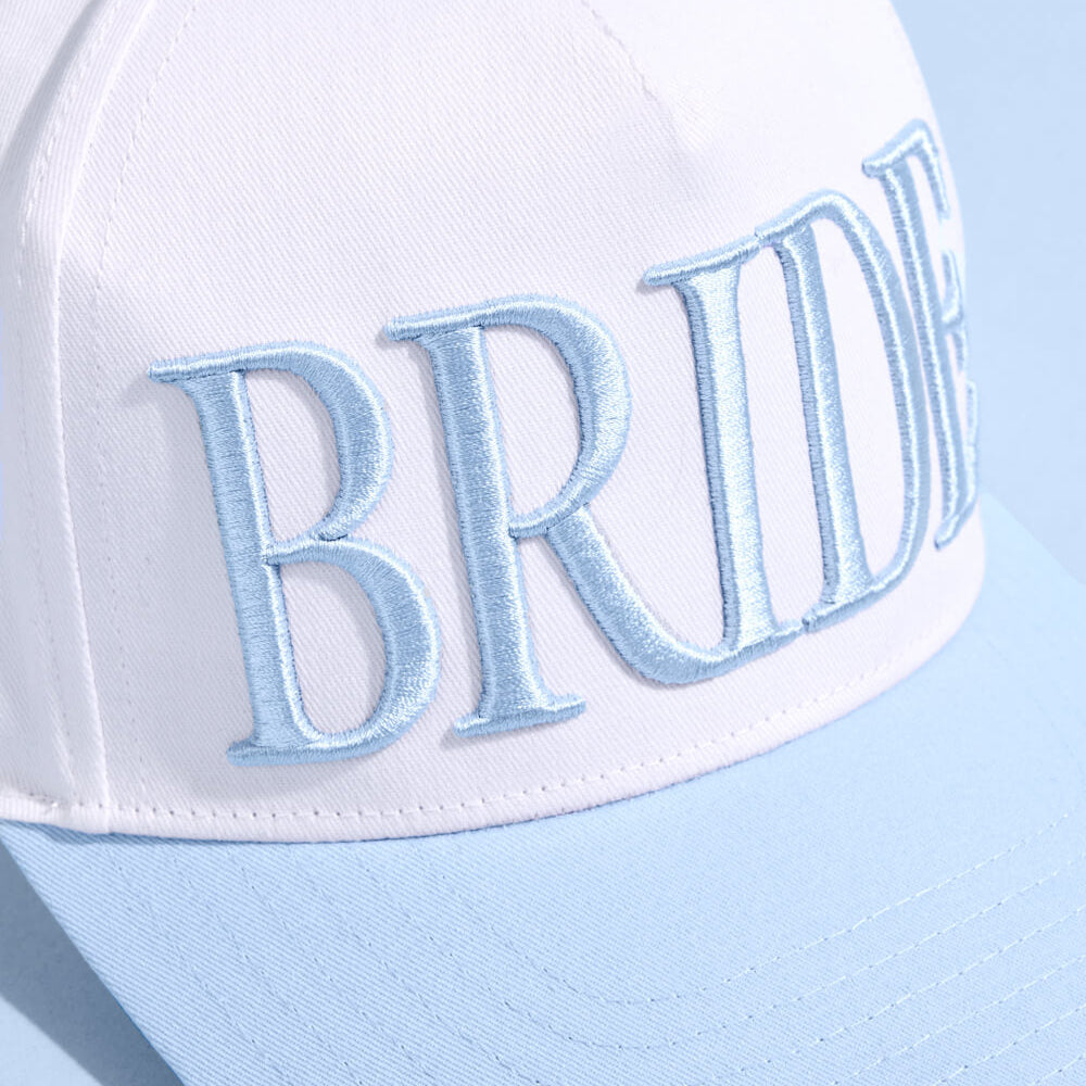 White cap with 'BRIDE' embroidered on it against a light blue background