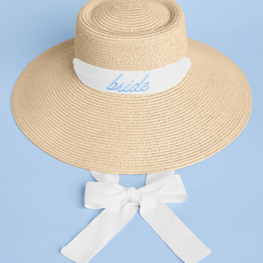 Beige sun hat with white ribbon and 'bride' embroidery on a light blue background