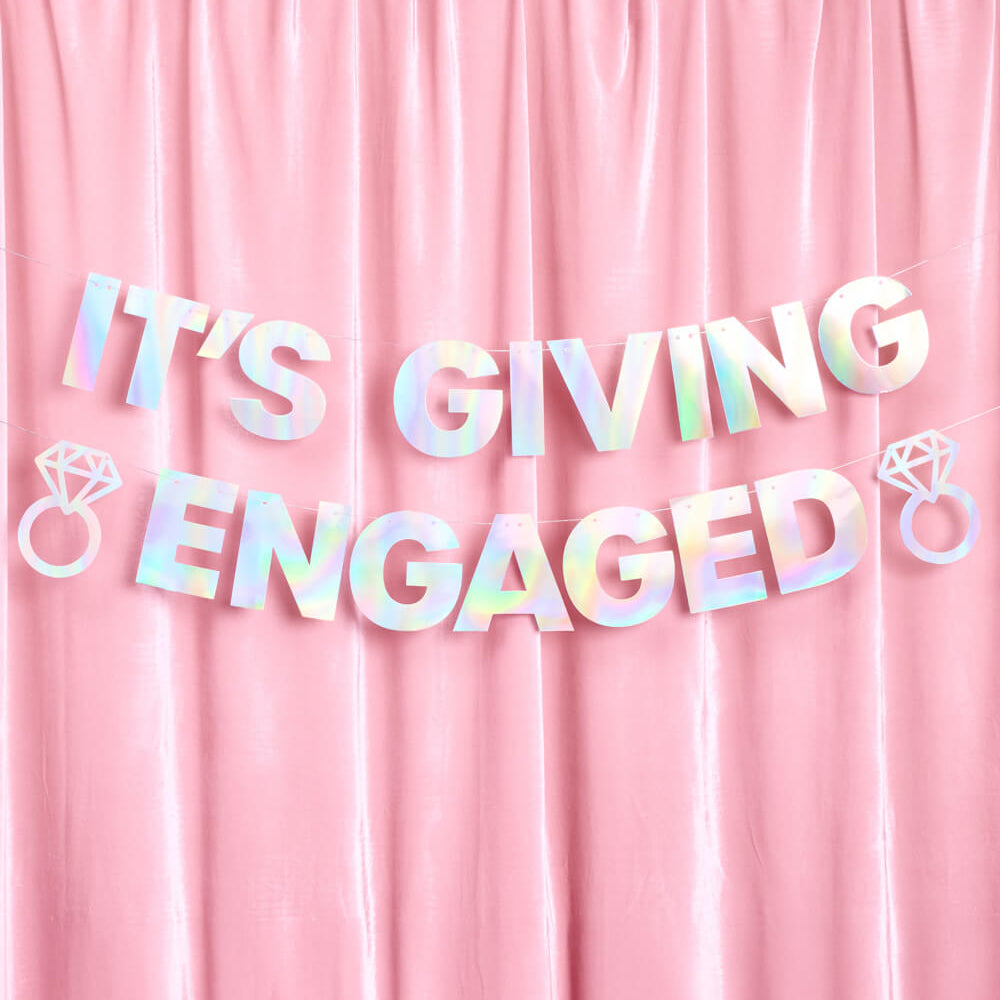 Holographic 'It's Giving Engaged' banner on a pink curtain background