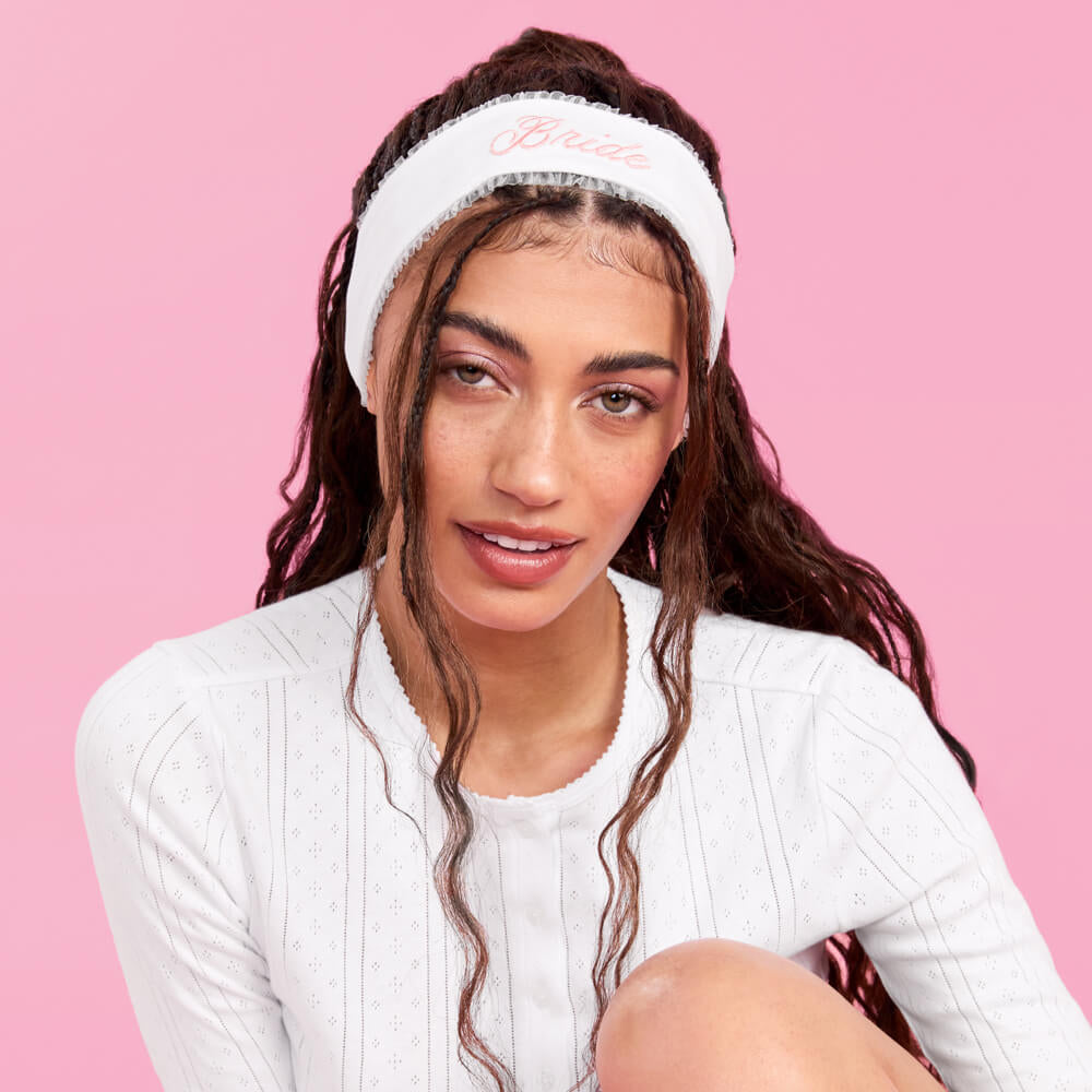 Woman wearing a white headband with text on a pink background