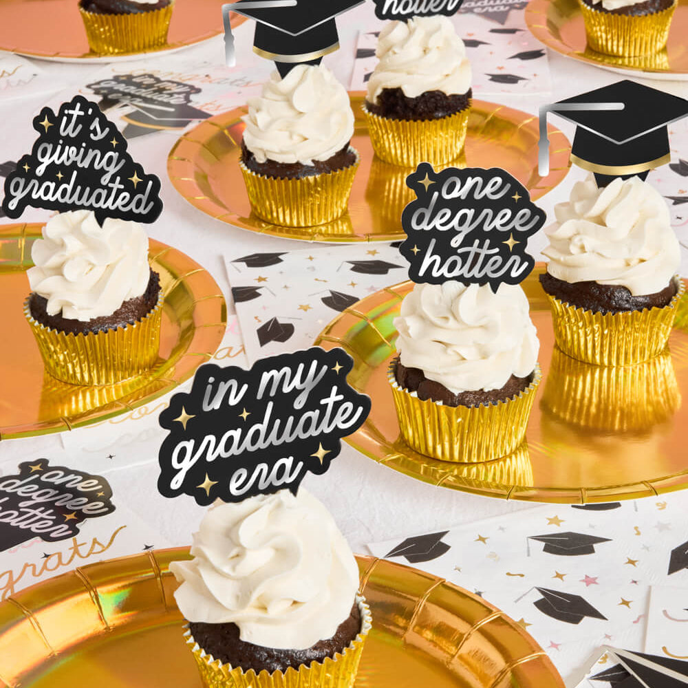 Graduation-themed cupcakes with decorative toppers on gold plates.