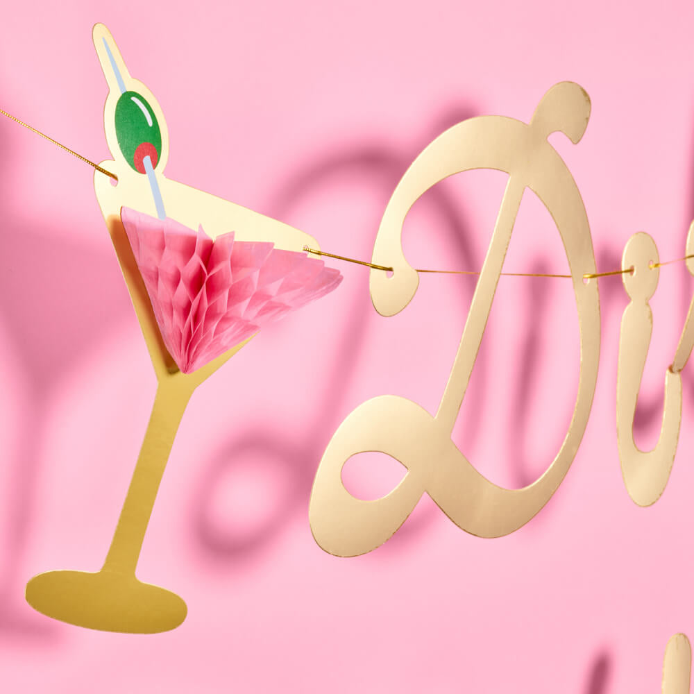Gold 'Divine' letter banner with a cocktail decoration on a pink background