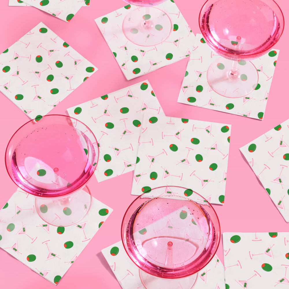 Martini themed party napkins arranged with cocktail glasses and party confetti for bachelorette decor