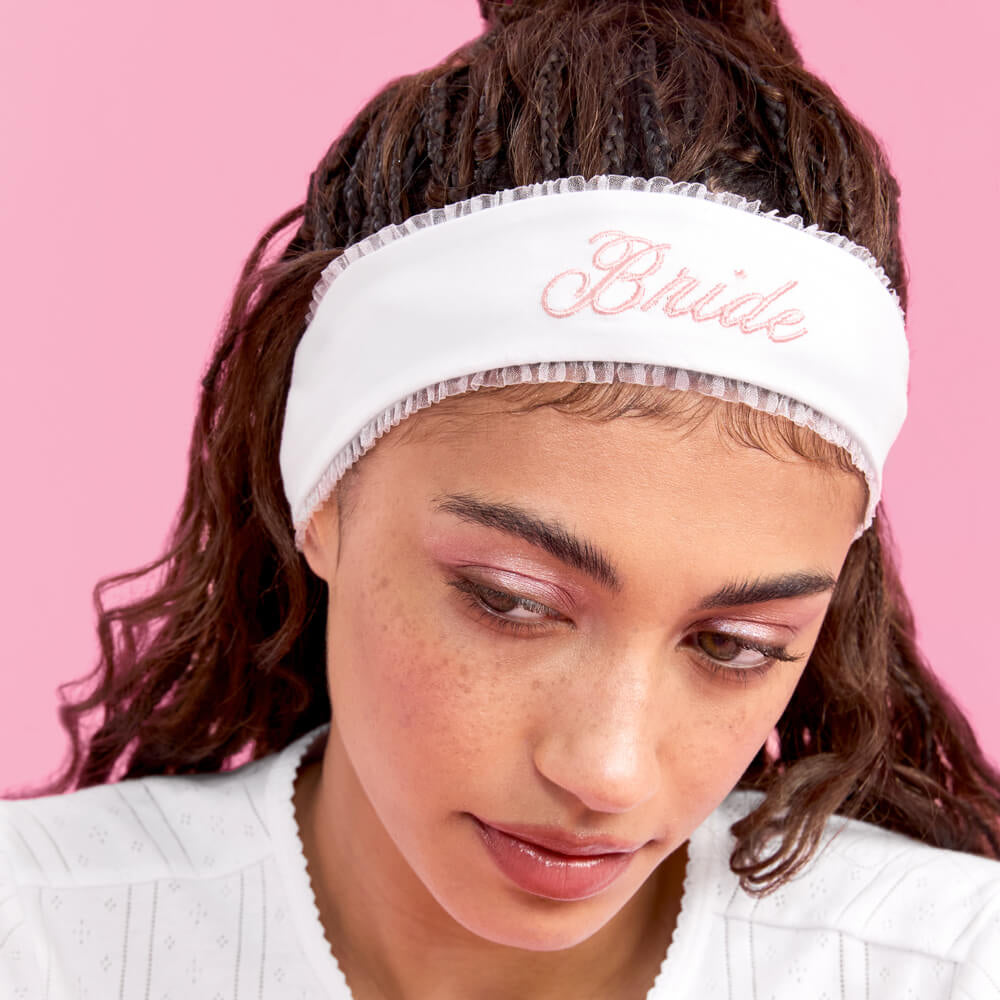 Person wearing a white headband with 'Bride' text against a pink background