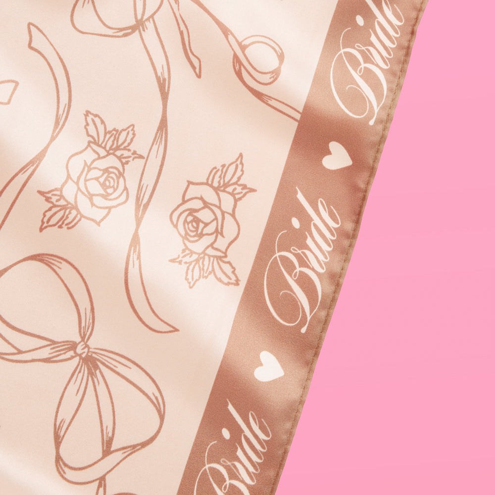 Decorative scarf with floral patterns and 'Bride' text on a pink background