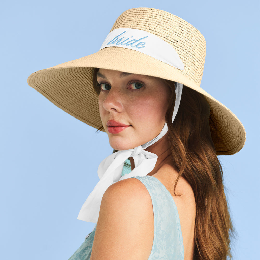 Woman wearing a straw hat with a white band and 'bride' embroidery against a blue background