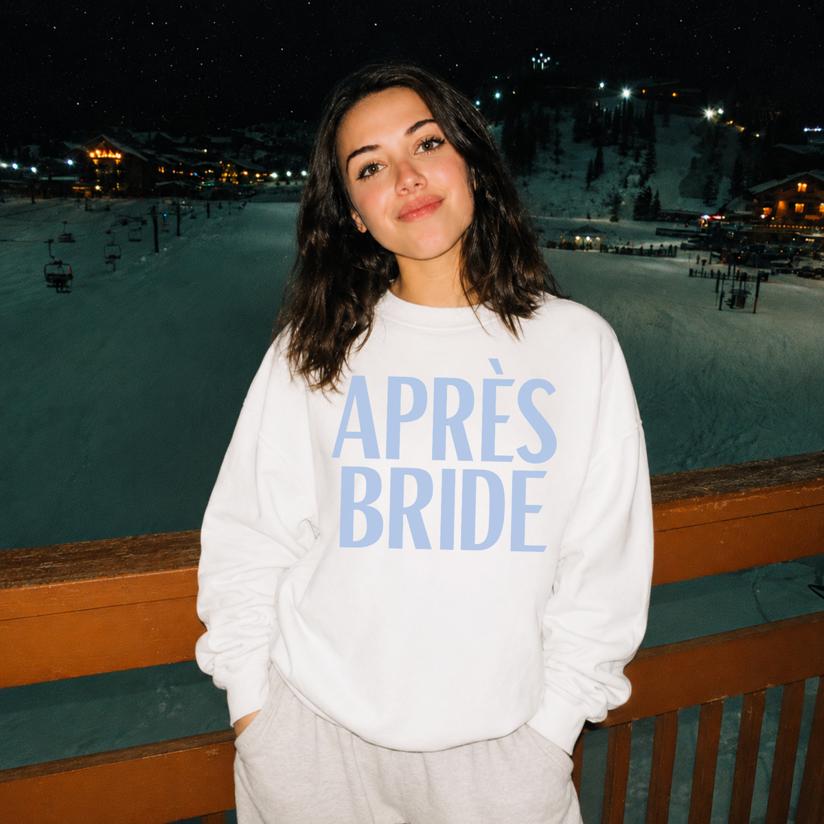 Bride wearing white Après Bride crewneck sweatshirt at snowy ski resort
