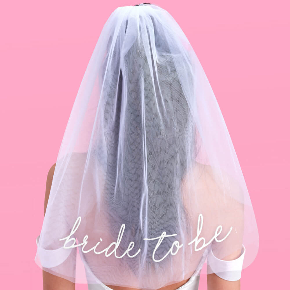 Person wearing a white veil with 'bride to be' text on a pink background