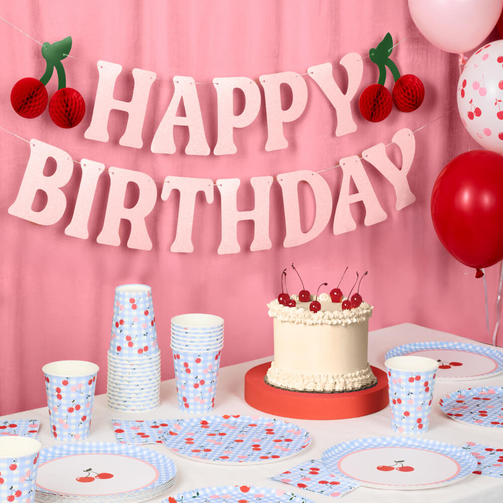 Cherry themed birthday table with blue gingham plates, cups, napkins, and cherry cake