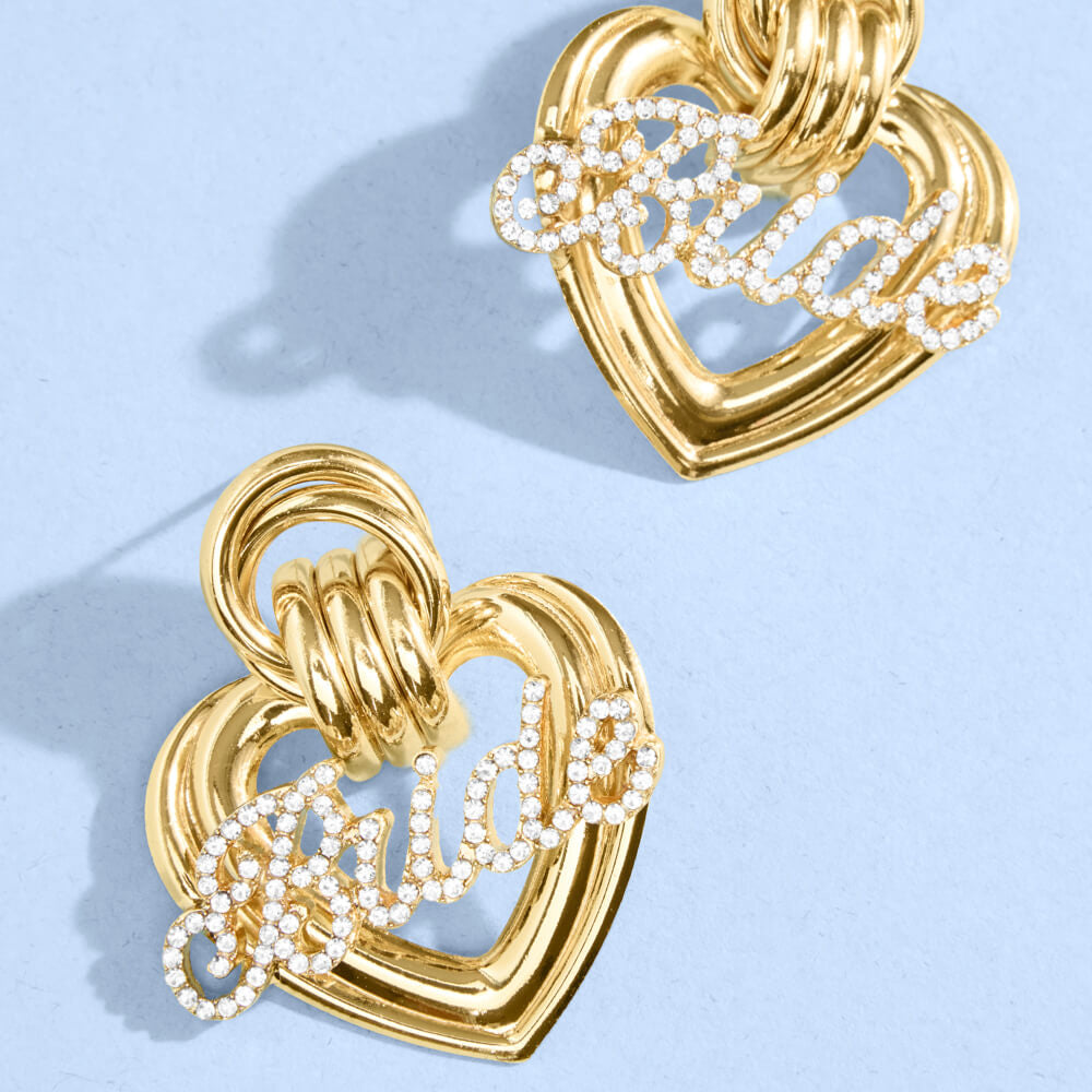 Gold heart earrings with rhinestone “Bride” lettering on light blue background