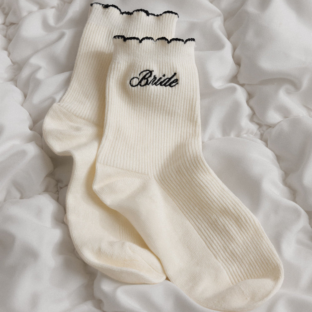 White socks with 'Bride' embroidery on a textured white surface