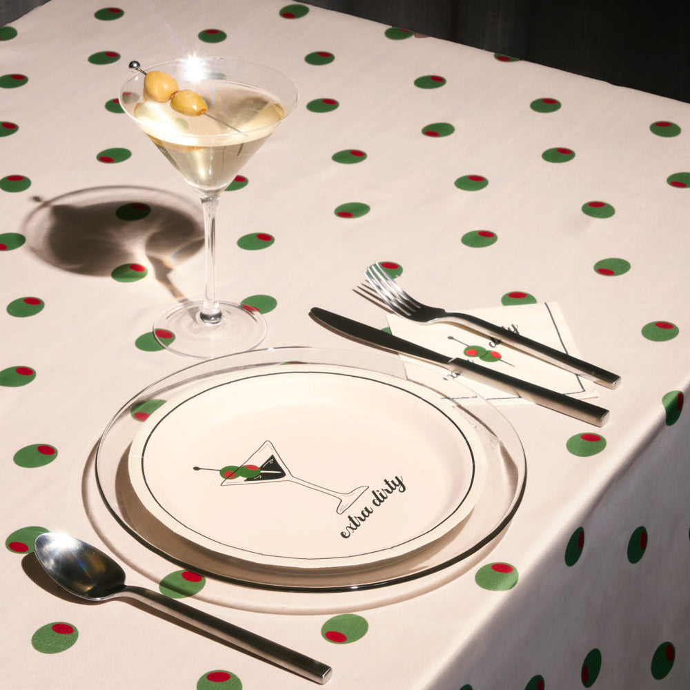 Dinner setting with a glass of cocktail, plate, and cutlery on a polka dot tablecloth.