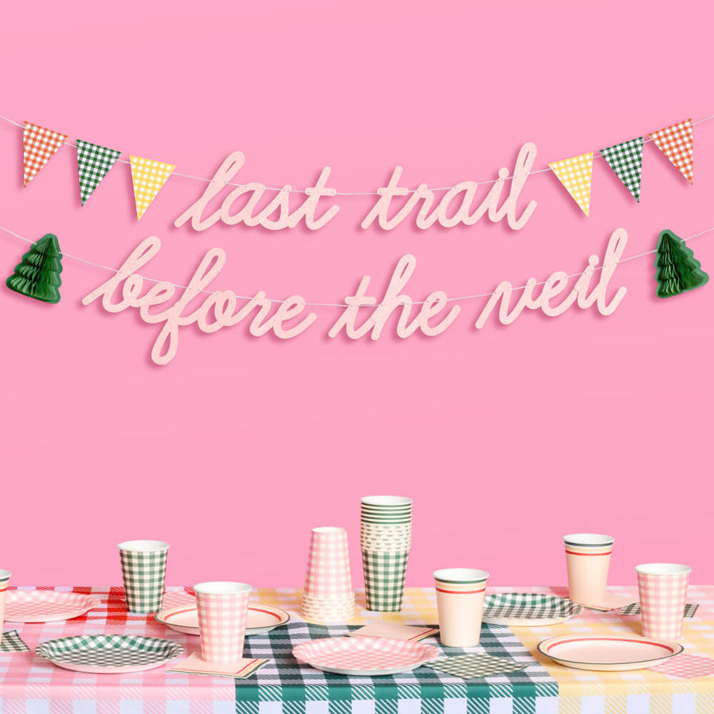 Decorative sign with 'last trail before the veil' text on a pink background with a table set for a celebration.