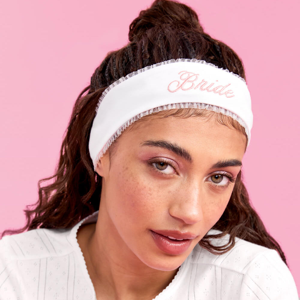 Woman wearing a white headband with 'Bella' text on a pink background