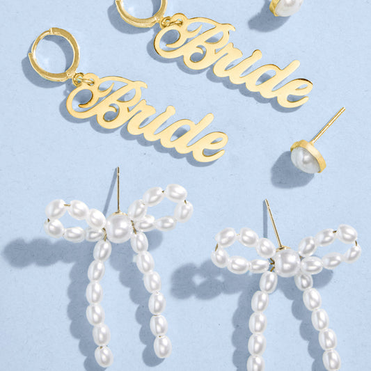 Gold 'Bride' earrings and pearl bow earrings on a light blue background