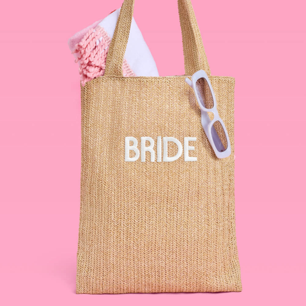 Beige tote bag with 'BRIDE' text on a pink background