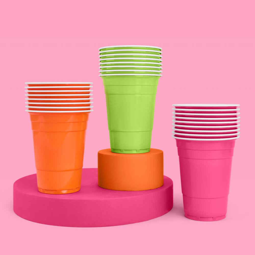 Colorful plastic cups stacked on a pink platform against a pink background