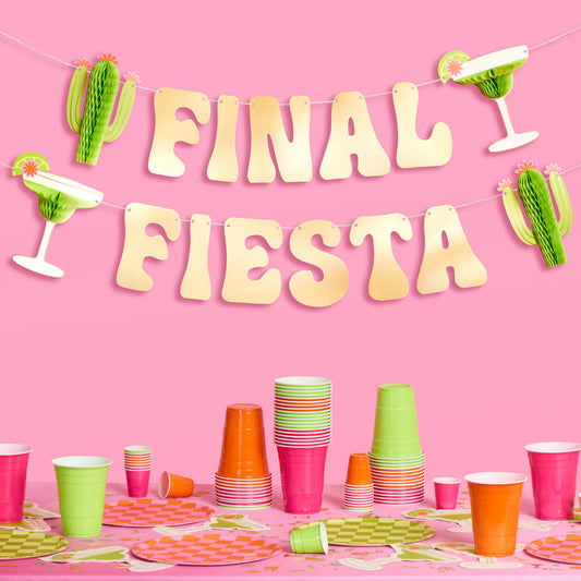 Party setup with 'Final Fiesta' banner, cups, and decorations on a pink background