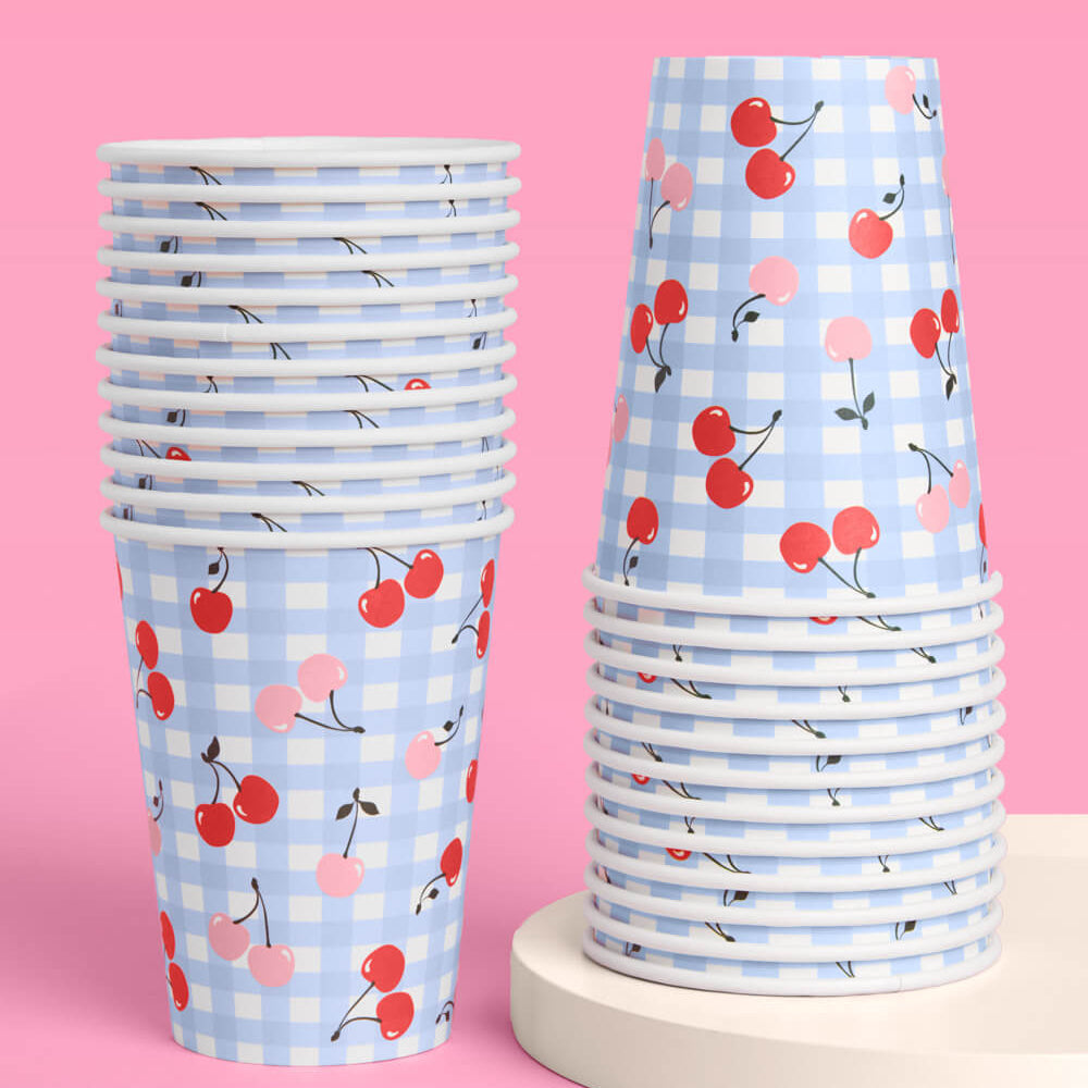 Stacks of paper cups with cherry pattern on a pink background