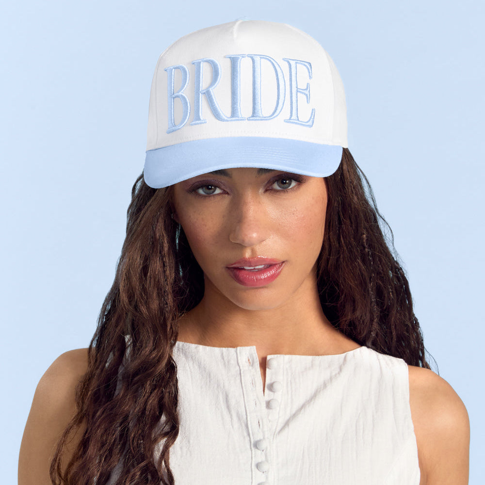 Woman wearing a white cap with 'BRIDE' text on a light blue background