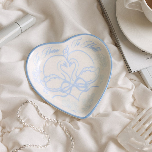 Heart-shaped ceramic dish with blue design on a white fabric background
